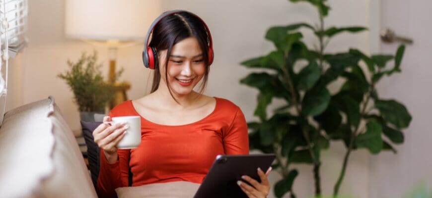 A woman reading a tablet while sitting on a living room couch